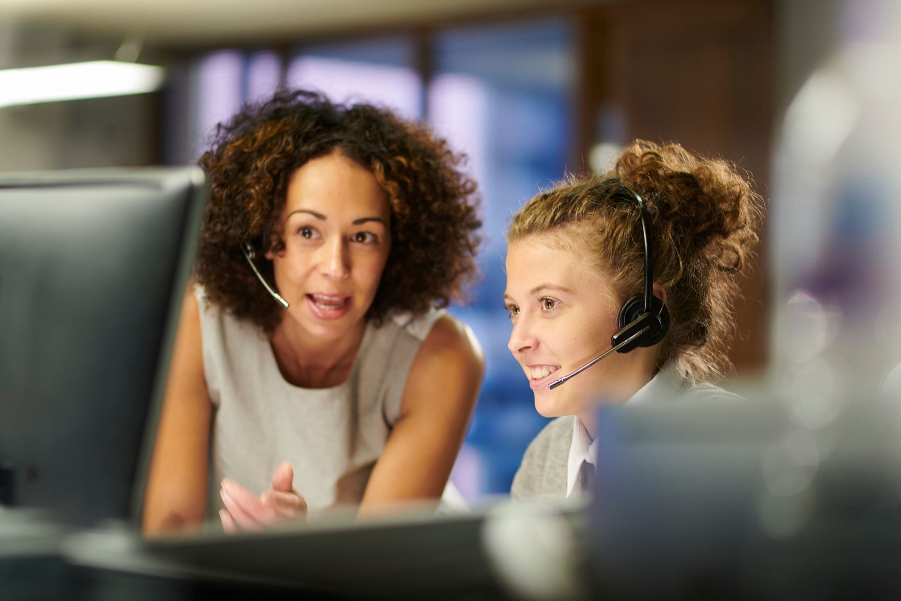 Two contact center agents collaborating at a computer.